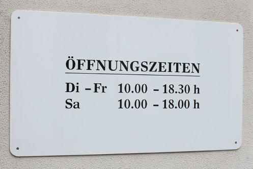 Fotografie eines Schildes mit Ladenöffnungszeiten